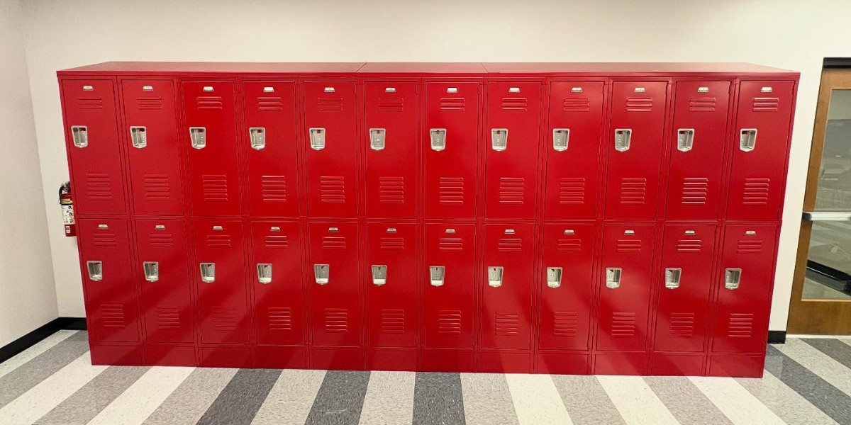 A long bank of red metal lockers tiered in two rows against a white wall.