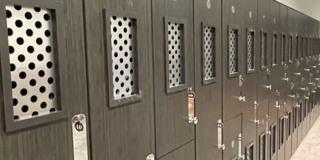 Row of dark gray lockers featuring rectangular, perforated metal ventilation panels.